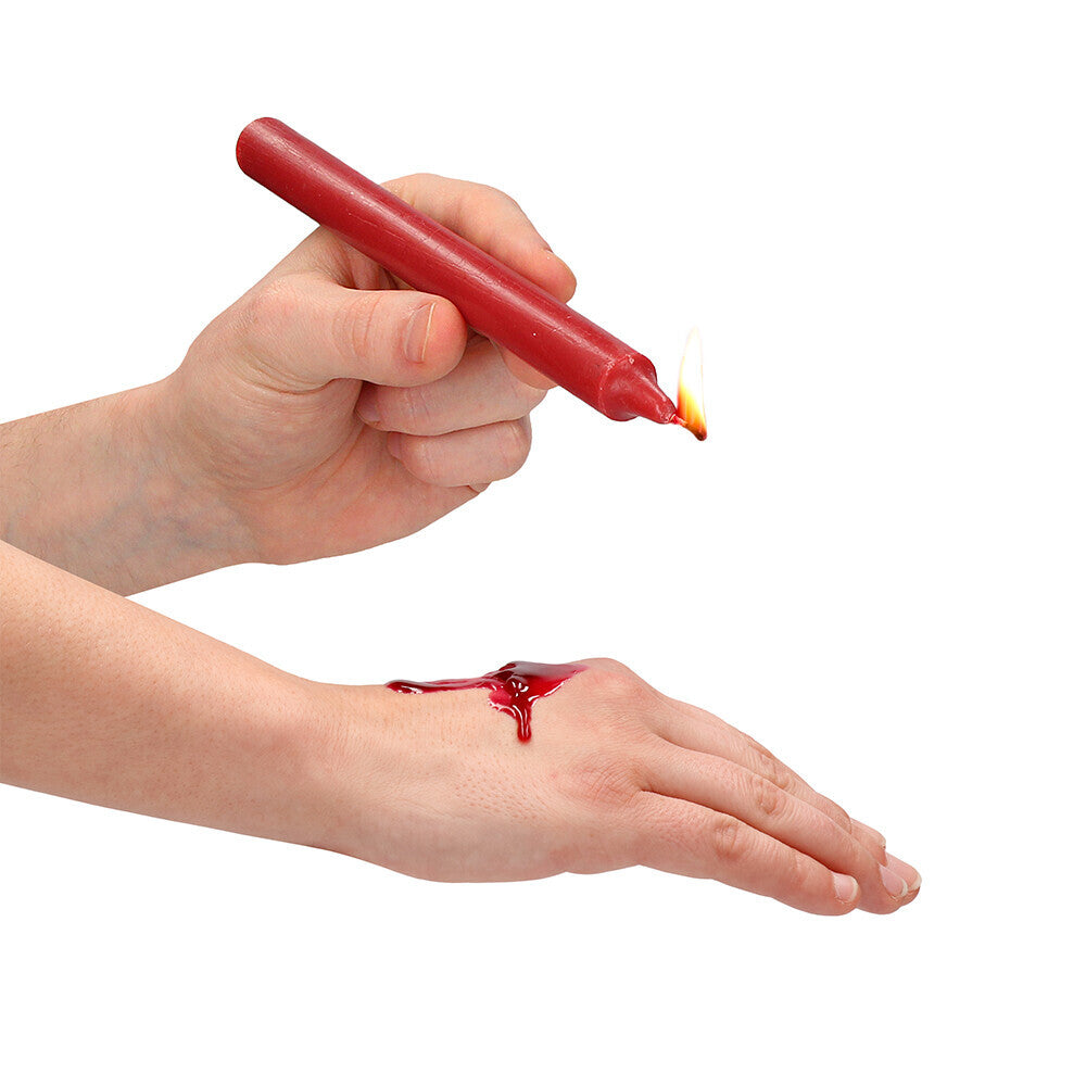 Red teasing wax candle dripping on a hand.