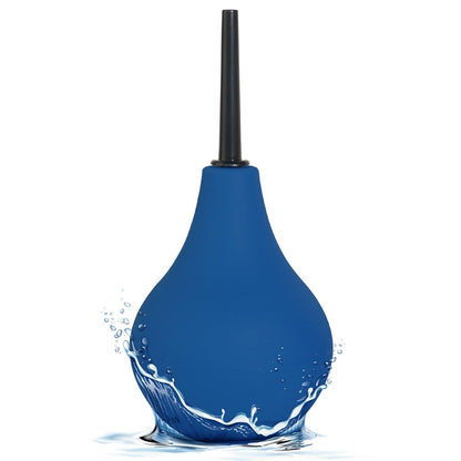 Blue enema bulb with a black nozzle, standing in a splash of water.