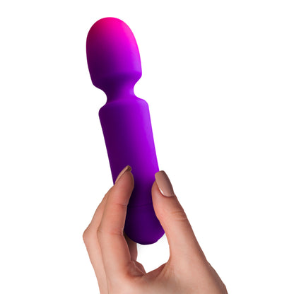 A hand holds a purple wand vibrator, top fades pink.