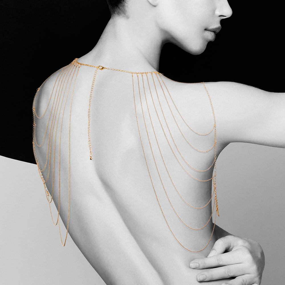 Golden whispers grace her back. The Bijoux Indiscrets shoulder jewellery, a cascade of allure.
