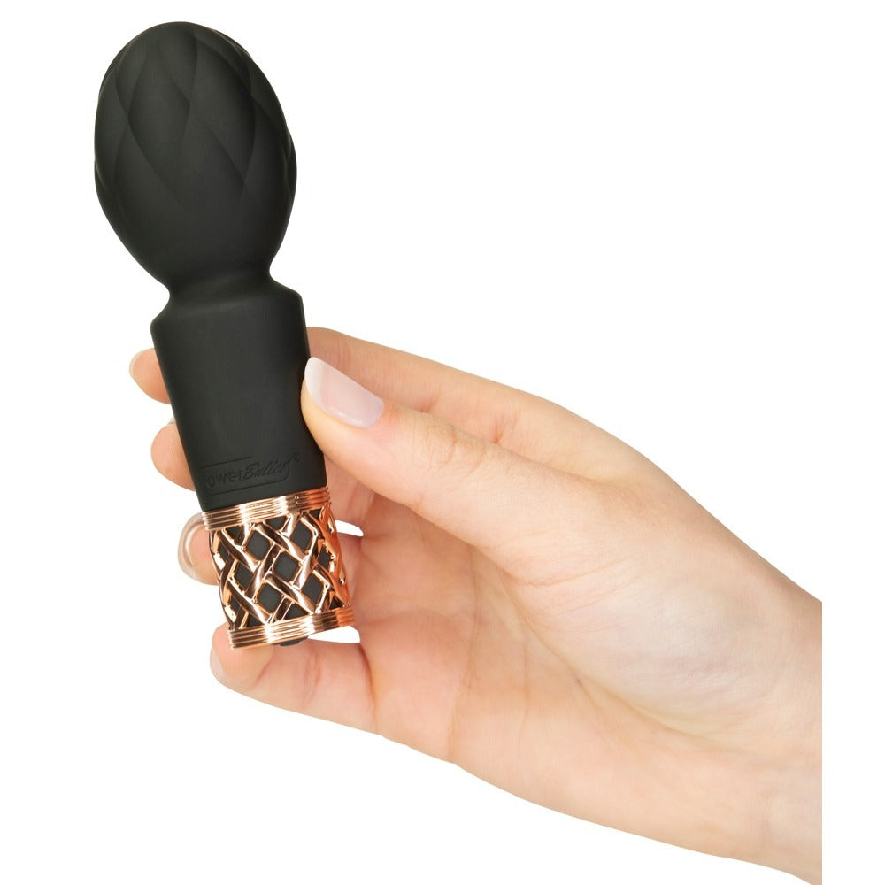Hand holding Pillow Talk Secrets Pleasure Mini Massager; black with rose gold lattice detail.

