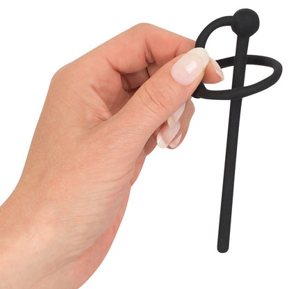 Hand holding black penis plug with glans ring from You2Toys.