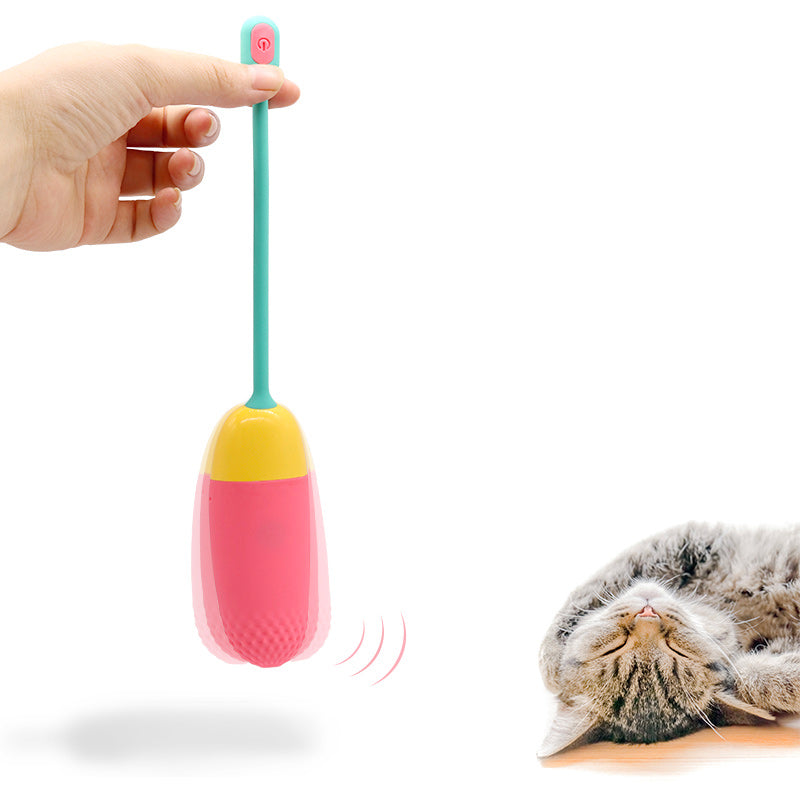 A pink Vini Lite vibrator being held by a hand near a blissed-out kitty.
