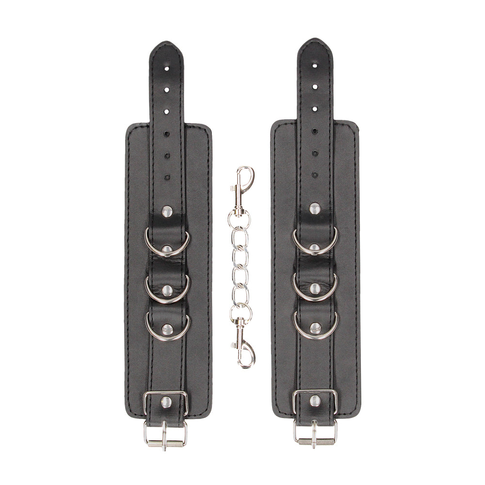 Pair of black leather wrist restraints with connecting chain.