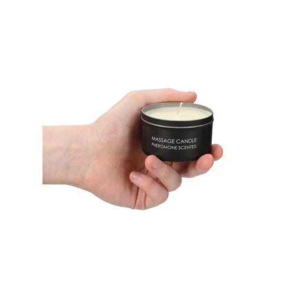 Hand holding a Pheromone scented massage candle tin.
