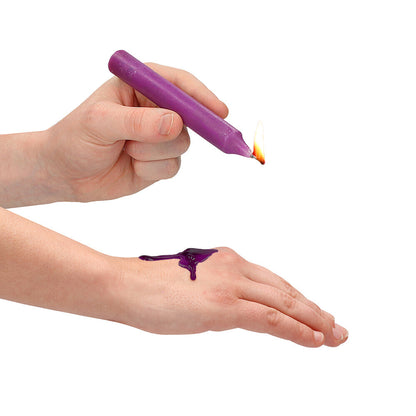 Purple teasing wax being dripped onto a hand.