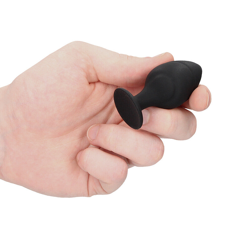 Black silicone butt plug being held in hand.
