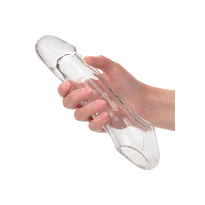Clear penis extender held in a manicured hand.