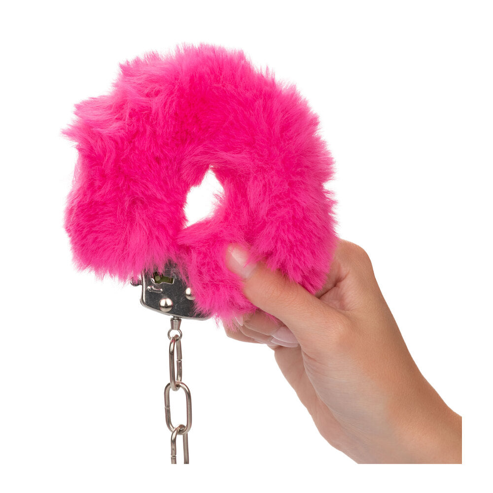 Pink fluffy cuffs held in hand.